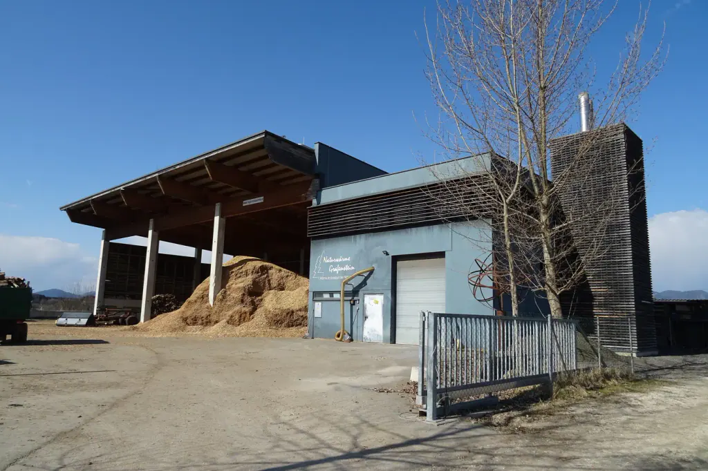 The open wood-chip hall of a district heating plant, with chips heaped inside