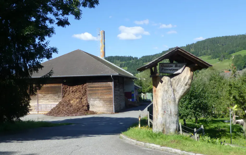 A village biomass heating plant with wood chips stacked under its open roof